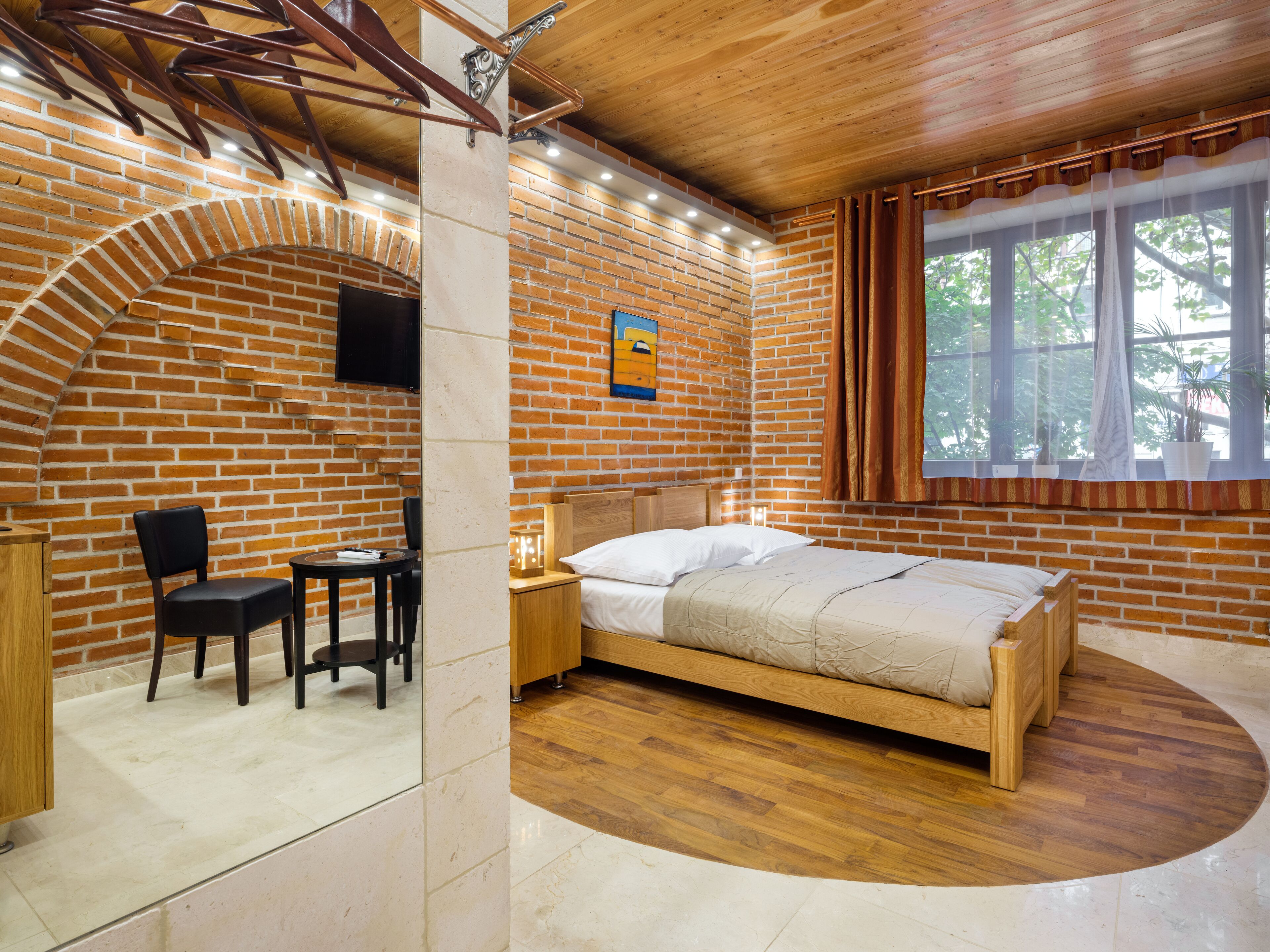 Une chambre avec un mur en briques, un plafond en bois, un lit, un bureau et une chaise.