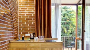 Une cuisine avec un mur en briques, un comptoir en bois et une vue sur un balcon agrémenté de plantes.