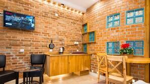 Une pièce chaleureuse avec un mur en briques, une table en bois, un téléviseur fixé au mur et une chaise.