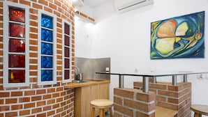 Une cuisine avec un mur en briques, un comptoir en bois, un tabouret et un tableau accroché au mur.