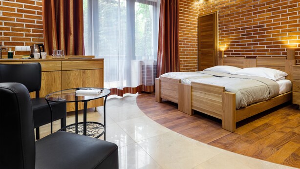 Une chambre moderne avec un plafond en bois, des murs en briques, un lit, un bureau et une chaise.