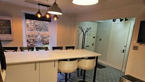 Une cuisine dotée d’un plan de travail en marbre, de chaises noires et de luminaires suspendus.