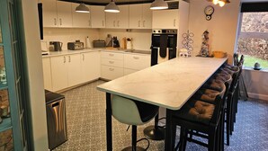 Une cuisine moderne avec des meubles blancs, un plan de travail en marbre et des luminaires suspendus.