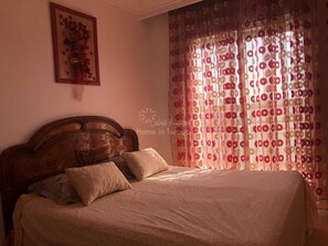 Ein Schlafzimmer mit einem hölzernen Kopfteil, einem Bett mit beigefarbener Bettwäsche und einem Blumenbild an der Wand.