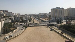 A cityscape with multi-story buildings, a wide road, and a sandy area. - Superb apartment for vaccinations (sousse)