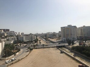 A cityscape with multi-story buildings, a wide road, and a sandy area. - Superb apartment for vaccinations (sousse)