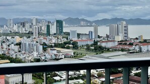 Un paisaje urbano con edificios residenciales y comerciales, una gran masa de agua al fondo y montañas en la distancia.