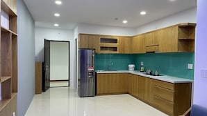 Una cocina moderna con armarios de madera, un refrigerador de acero inoxidable y un salpicadero color turquesa.