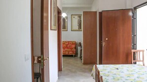 A room with a bed, a table, and a chair. There is a door leading to another room. - 1 bedroom amazing apartment in Locri (Locri)