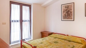 A bedroom with a bed, a nightstand, a window with curtains, and a framed picture on the wall. - 1 bedroom amazing apartment in Locri (Locri)