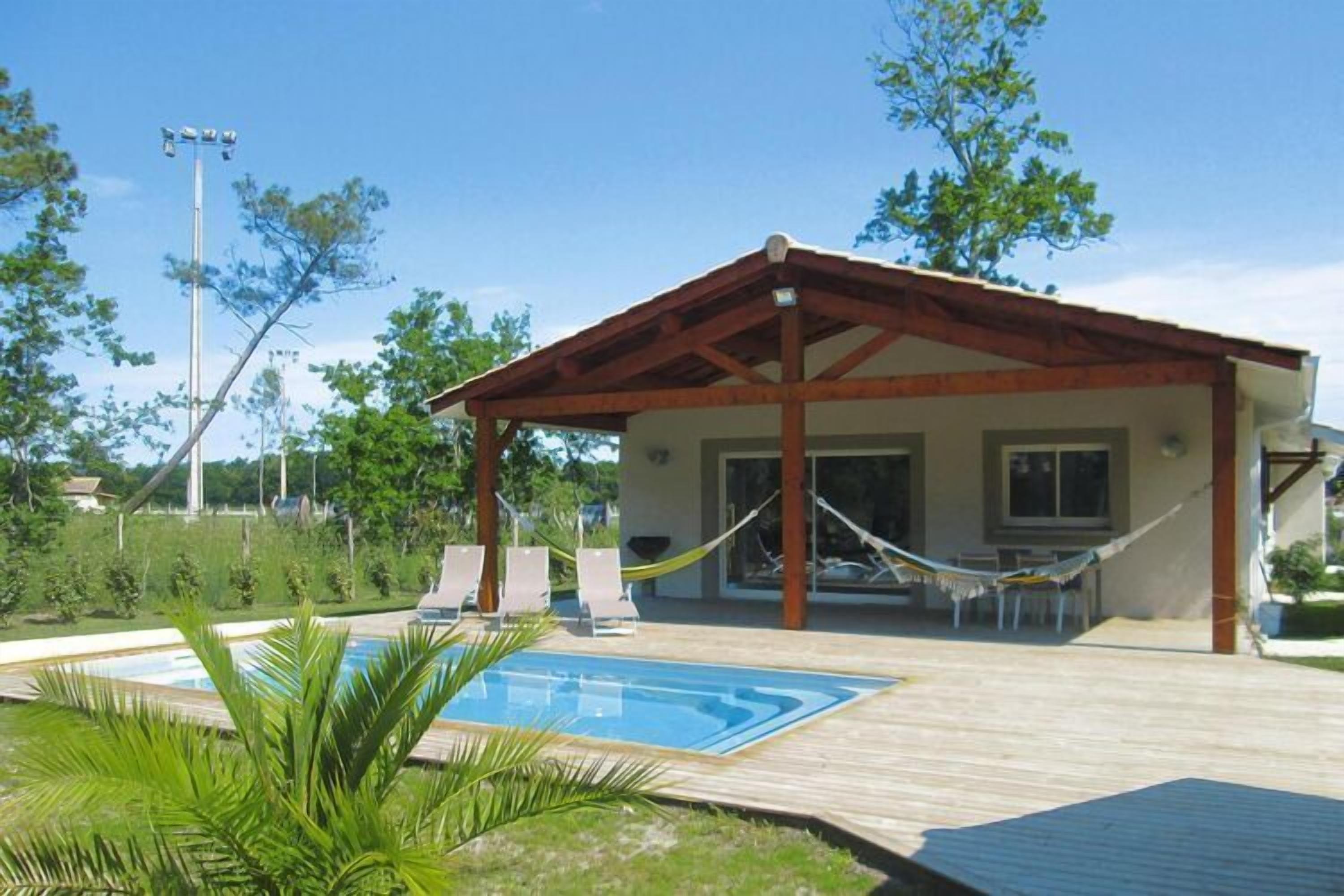 Un espacio al aire libre techado con piscina, sillas de descanso y una hamaca.