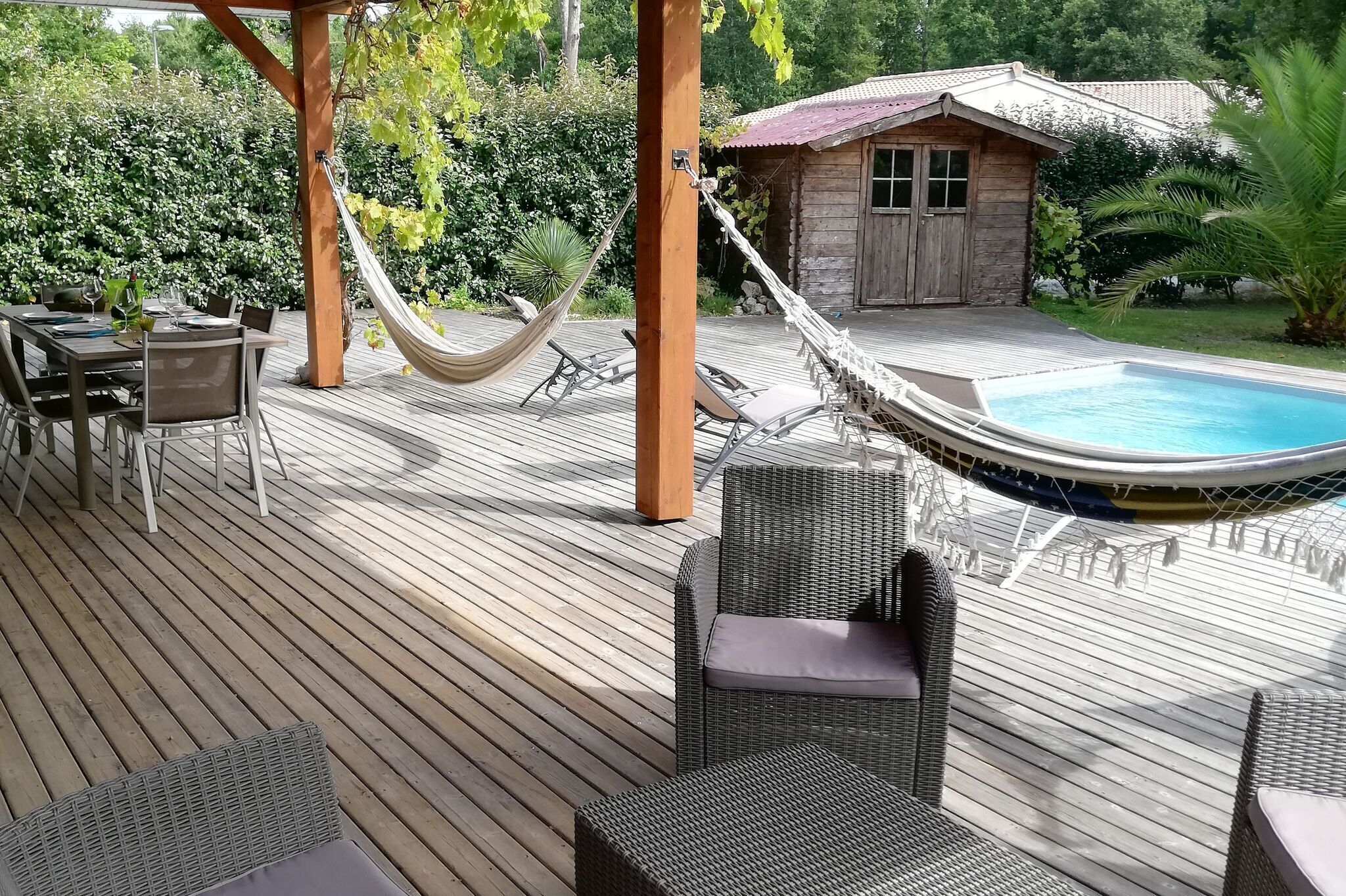 Un patio in legno con mobili da esterno, un'amaca e una piscina.