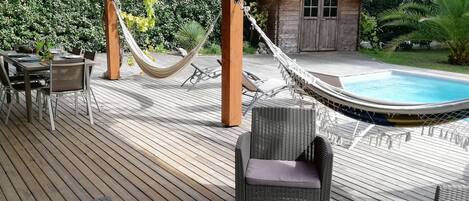 Un patio in legno con mobili da esterno, un'amaca e una piscina.