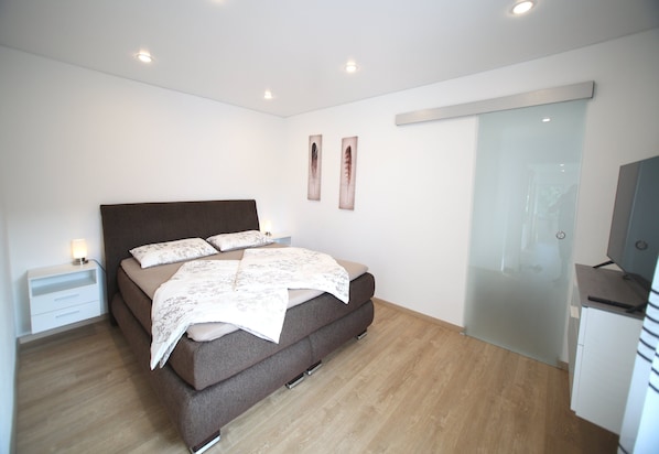 Une chambre à coucher avec un lit, une table de chevet et un bureau avec un ordinateur.