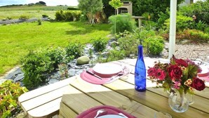 An outdoor dining table set with plates, cutlery, and a vase of flowers. - Holiday Home in Cléder near Les Amiets Beach (Cléder)