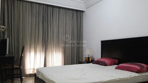 A hotel room with a large bed, a desk, a chair, and a lamp. - Great waterfront apartment (Sousse)