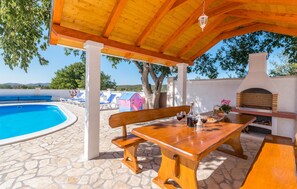 A covered outdoor area with a pool, wooden furniture, and a barbecue grill. - Nice home in Stankovci (Stankovci)