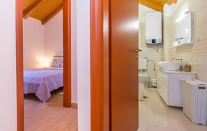 A hotel room with a bed, a bedside table, and a bathroom with a sink, toilet, and shower. - Nice home in Stankovci (Stankovci)