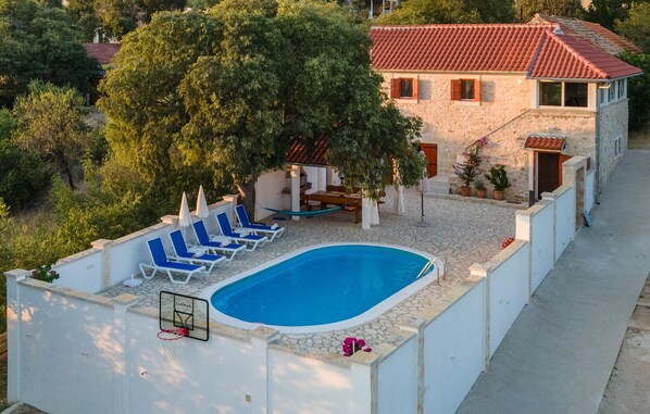 A swimming pool with blue water, surrounded by white walls and a basketball hoop. - Nice home in Stankovci (Stankovci)
