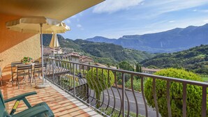 Ein Balkon mit Blick auf eine gebirgige Landschaft, einem Tisch mit Stühlen und einer Blumentopf.