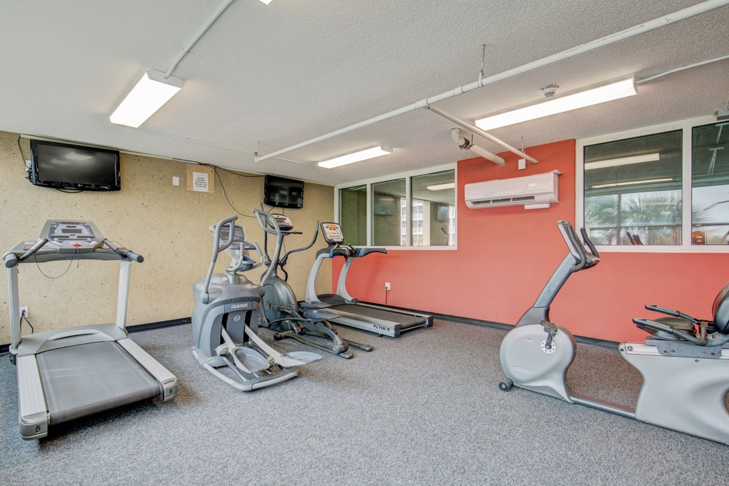 Et fitnesscenter med løbebånd, crosstrainere og en motionscykel.