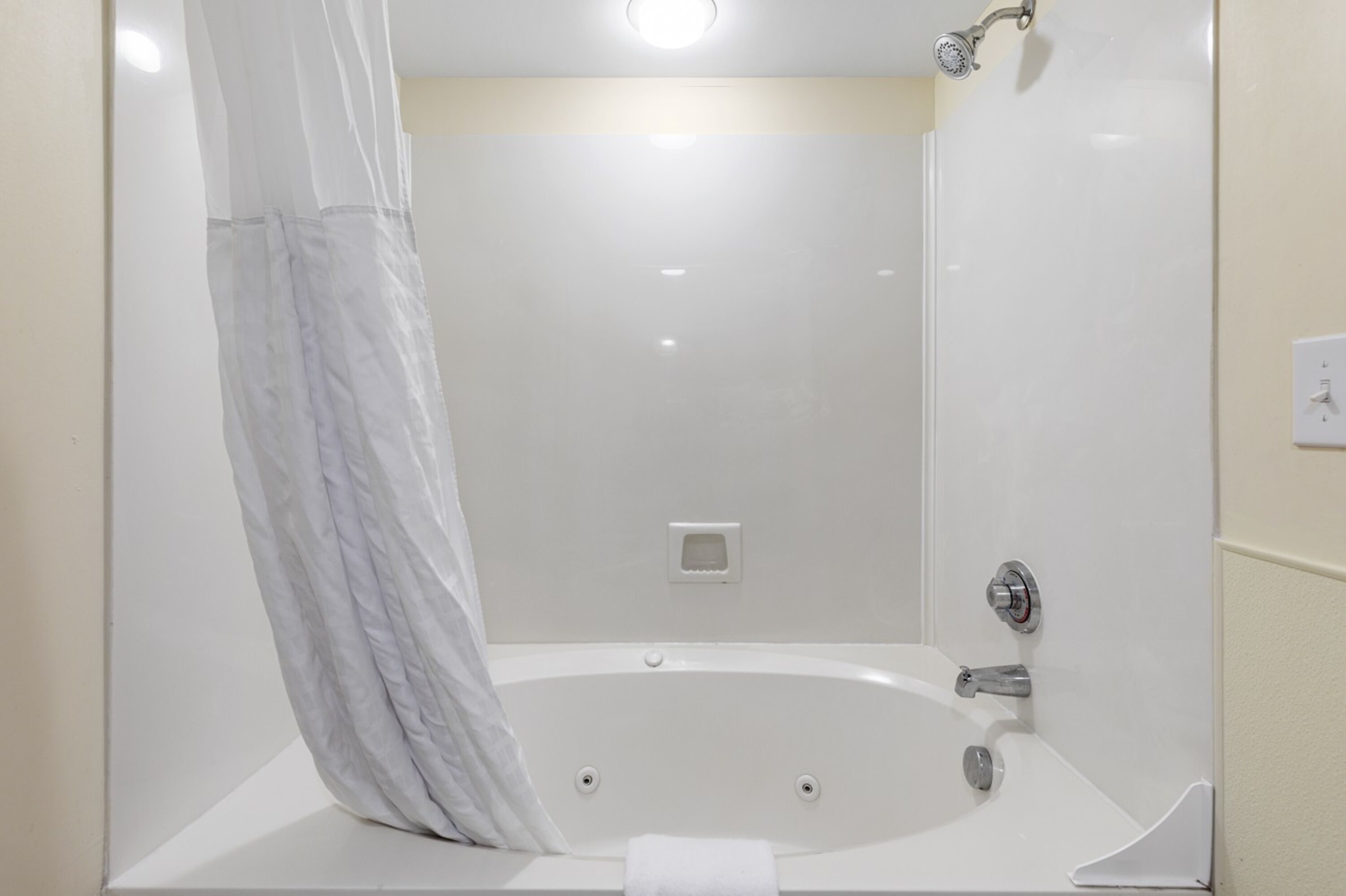 A modern bathroom with a large bathtub, a shower area, and a toilet.