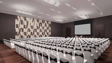 A conference room with rows of white chairs, a large screen, and a patterned wall.