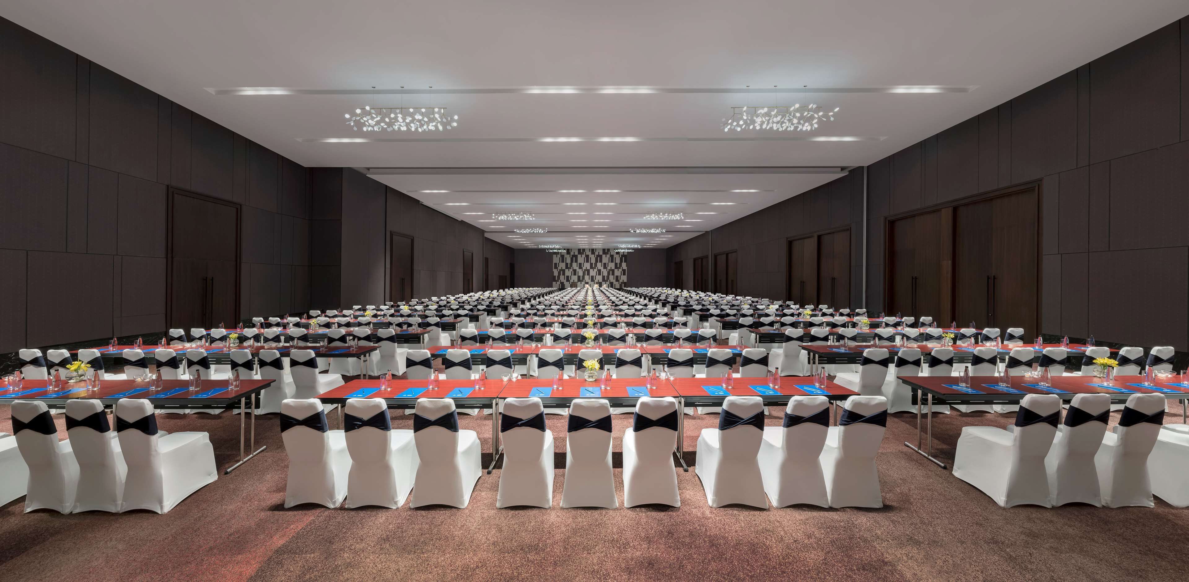 A conference room with rows of tables and chairs, equipped with nameplates and water bottles.