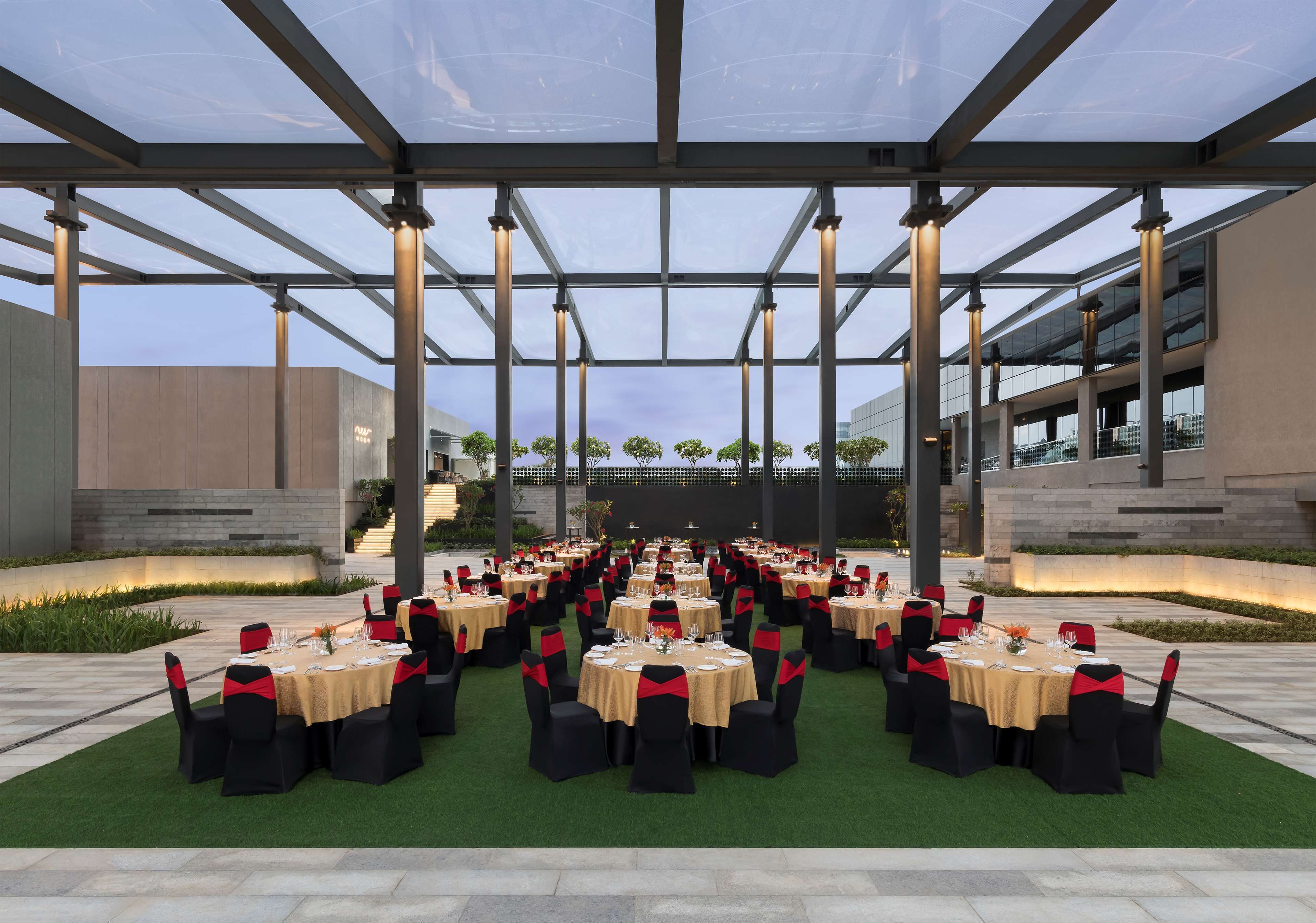 An outdoor dining area with multiple round tables, each set with chairs and table settings.