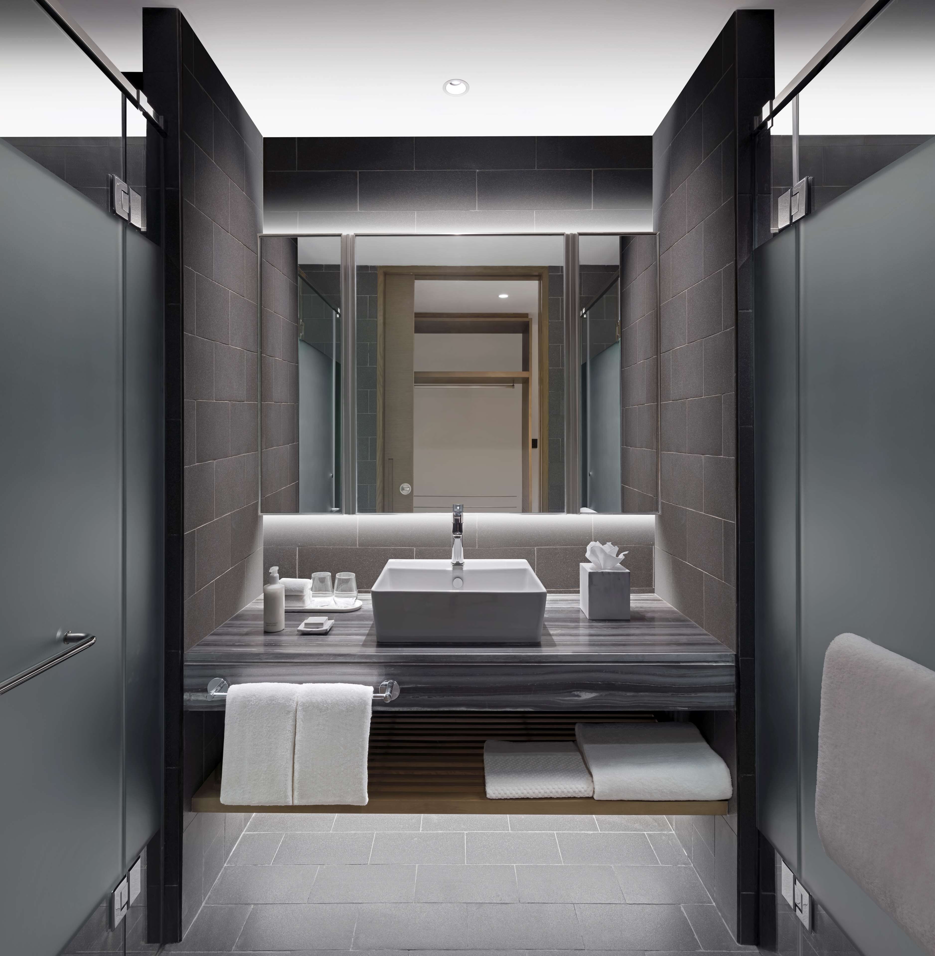 A modern bathroom with a large mirror, a rectangular sink, and a towel rack.