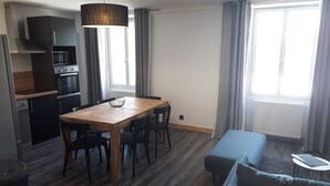 Une cuisine moderne dotée d’appareils électroménagers intégrés, une table à manger avec des chaises, un banc et une petite table d’appoint.