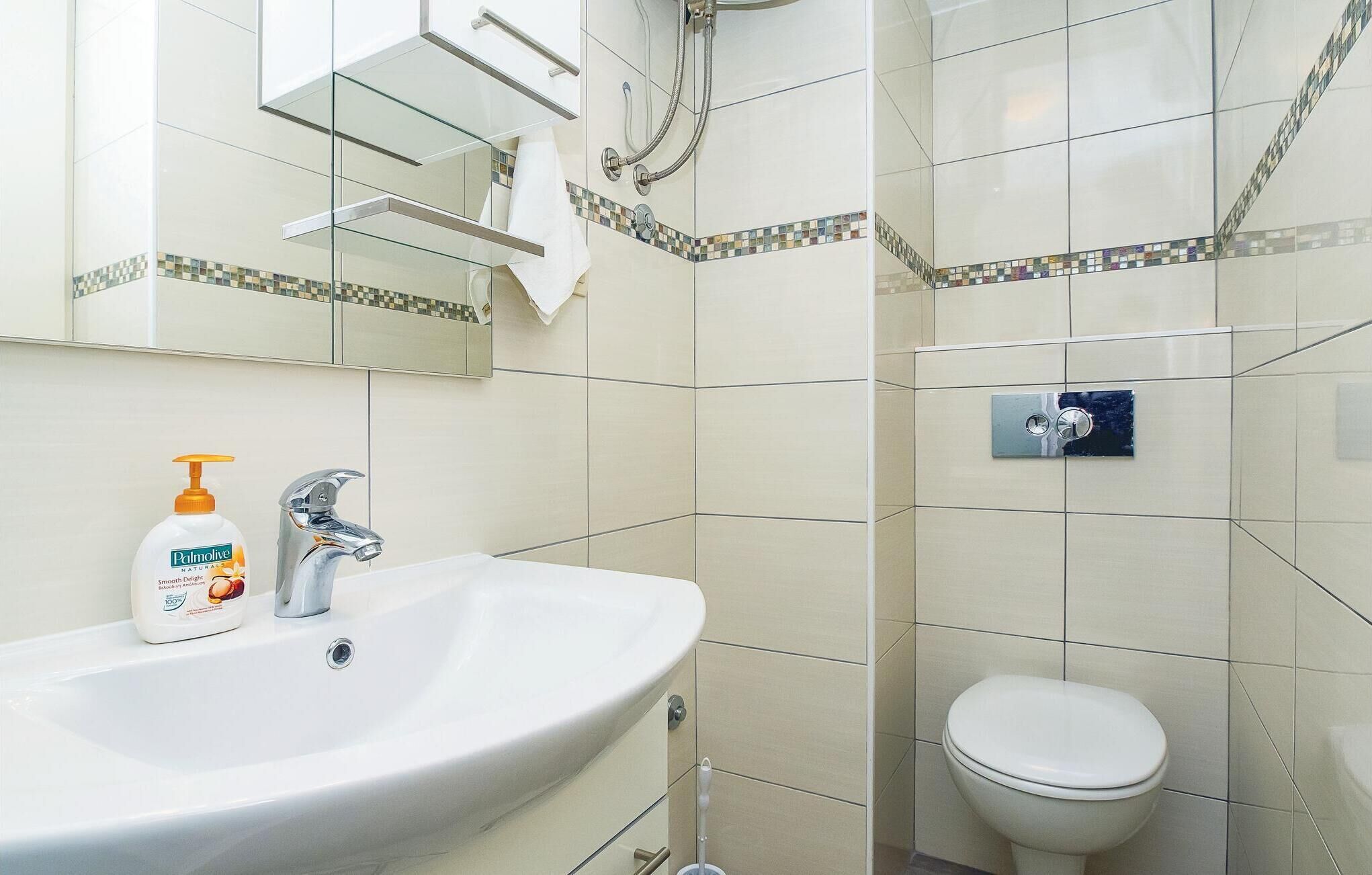 Ein Badezimmer mit Waschbecken, Spiegel, Toilette und Duschbereich.