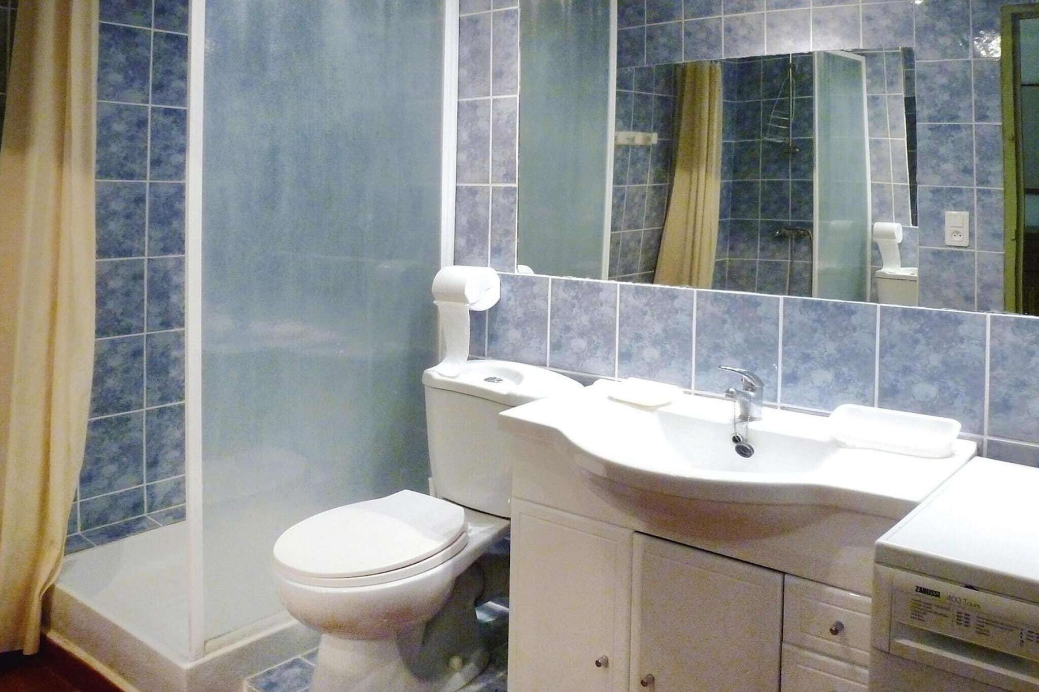 A bathroom with a toilet, sink, and mirror.