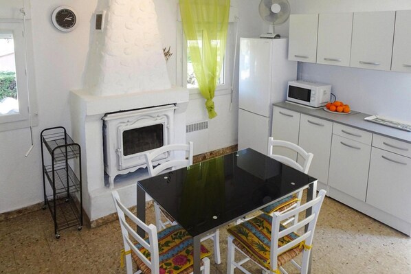 Cocina compacta con estufa, microondas y armarios blancos.