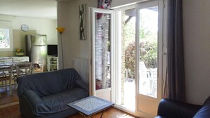 A living room with a grey sofa, a small table, and a sliding glass door leading to a balcony. - Villa in Provence near Mont Ventoux (Vaison-la-Romaine)