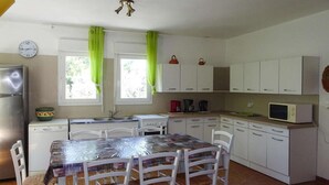 A compact kitchen with white cabinets, a microwave, a sink, and a dining table with chairs. - Villa in Provence near Mont Ventoux (Vaison-la-Romaine)