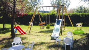 A playground with swings, a slide, and plastic chairs. - Villa in Provence near Mont Ventoux (Vaison-la-Romaine)