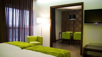 Een hotelkamer met twee bedden, een bureau, een stoel, een televisie en een eethoek.