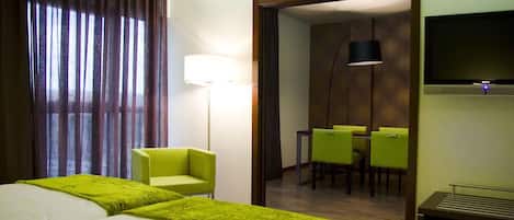 Una habitación de hotel con dos camas, un escritorio, una silla, un televisor y un comedor.