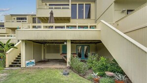 A two-story building with a covered patio area, a staircase, and potted plants.