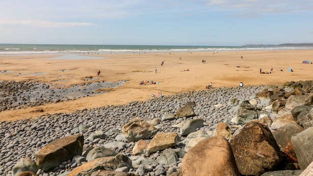 Une plage dont la partie avant est rocheuse et qui se prolonge par une zone de sable.