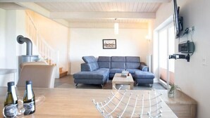 A modern living room with a grey sectional sofa, a wooden coffee table, and a metal drying rack. - Luxuriös ausgestattetes Ferienhaus über zwei Etagen (Dagebüll)