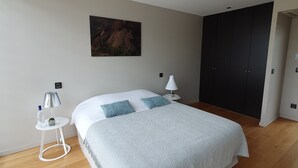 Ein Schlafzimmer mit einem Bett, einem Nachttisch mit Lampe, einem Wandbild und einem Kleiderschrank.