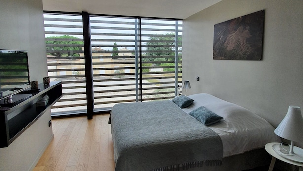 Ein modernes Schlafzimmer mit einem großen Bett, einem Fernseher und einem Balkon mit Rollläden.