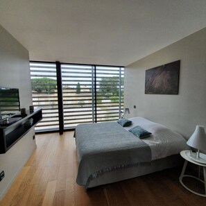 Ein modernes Schlafzimmer mit einem großen Bett, einem Fernseher und einem Balkon mit Rollläden.