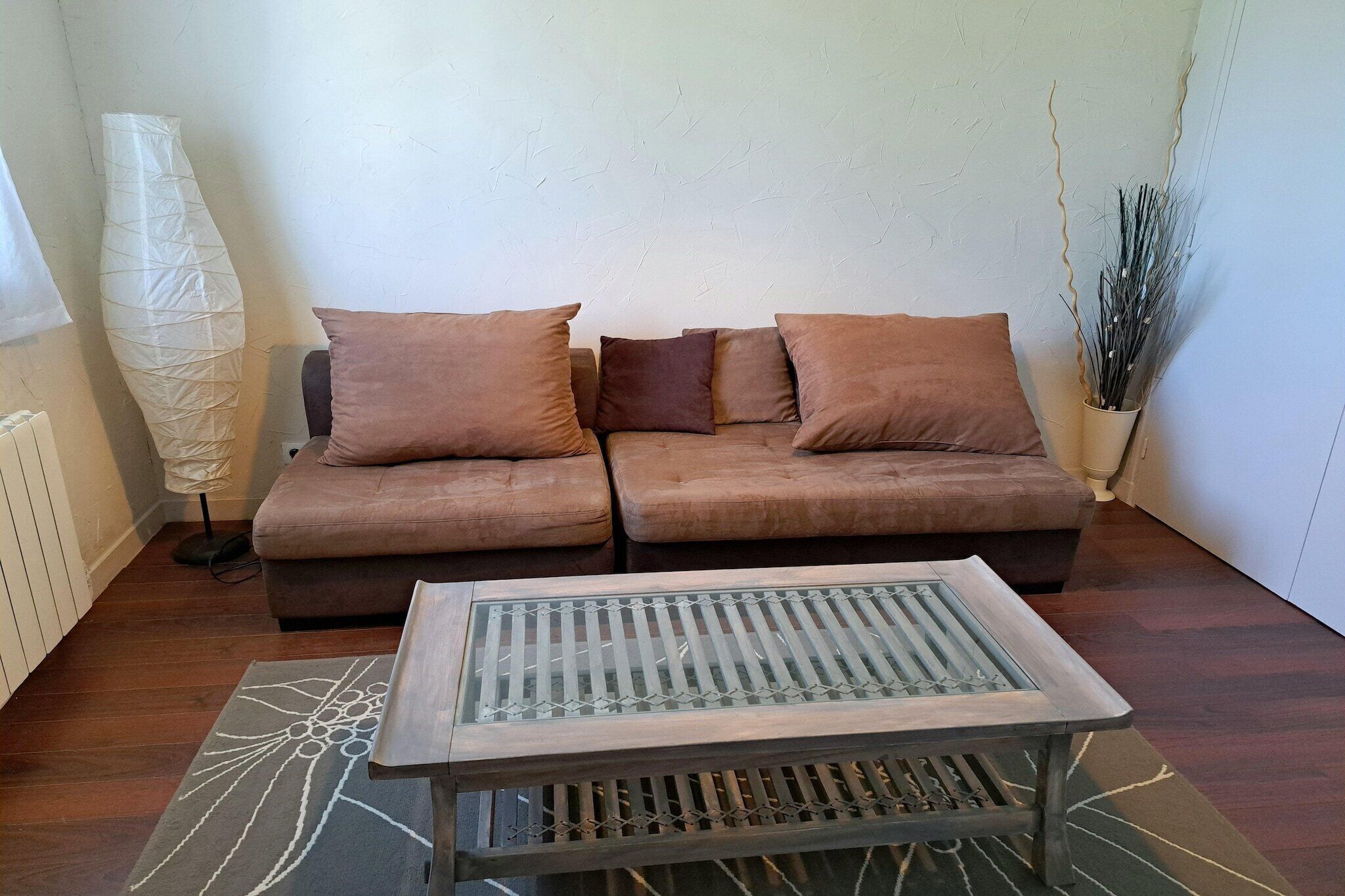 A living room with a sofa, a coffee table, and a floor lamp.