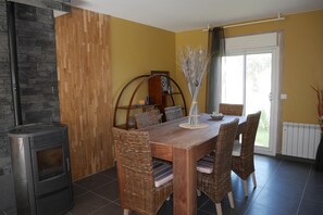 Enjoy meals in this cozy dining area with a wood-burning stove and a view of lush greenery.