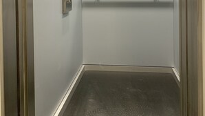 A narrow elevator with metallic walls and a reflective floor. - The Apartment is in a calm, quiet location at the Lake Balaton! (Keszthely)