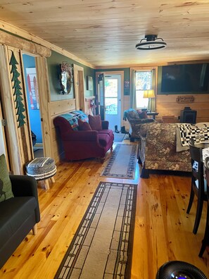Un acogedor interior de cabaña con pisos de madera, chimenea, mesa de comedor y sofá.