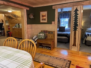 A cozy cabin interior with a dining area, a bed, and a bathroom.